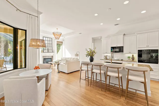 a living room with stainless steel appliances furniture a rug kitchen view and a large window