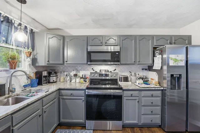 a kitchen with stainless steel appliances granite countertop a stove top oven a sink a dining table and chairs