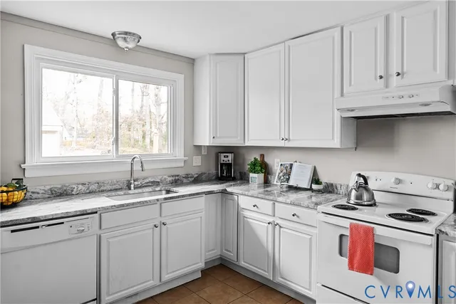 a kitchen with stainless steel appliances granite countertop white cabinets sink and window