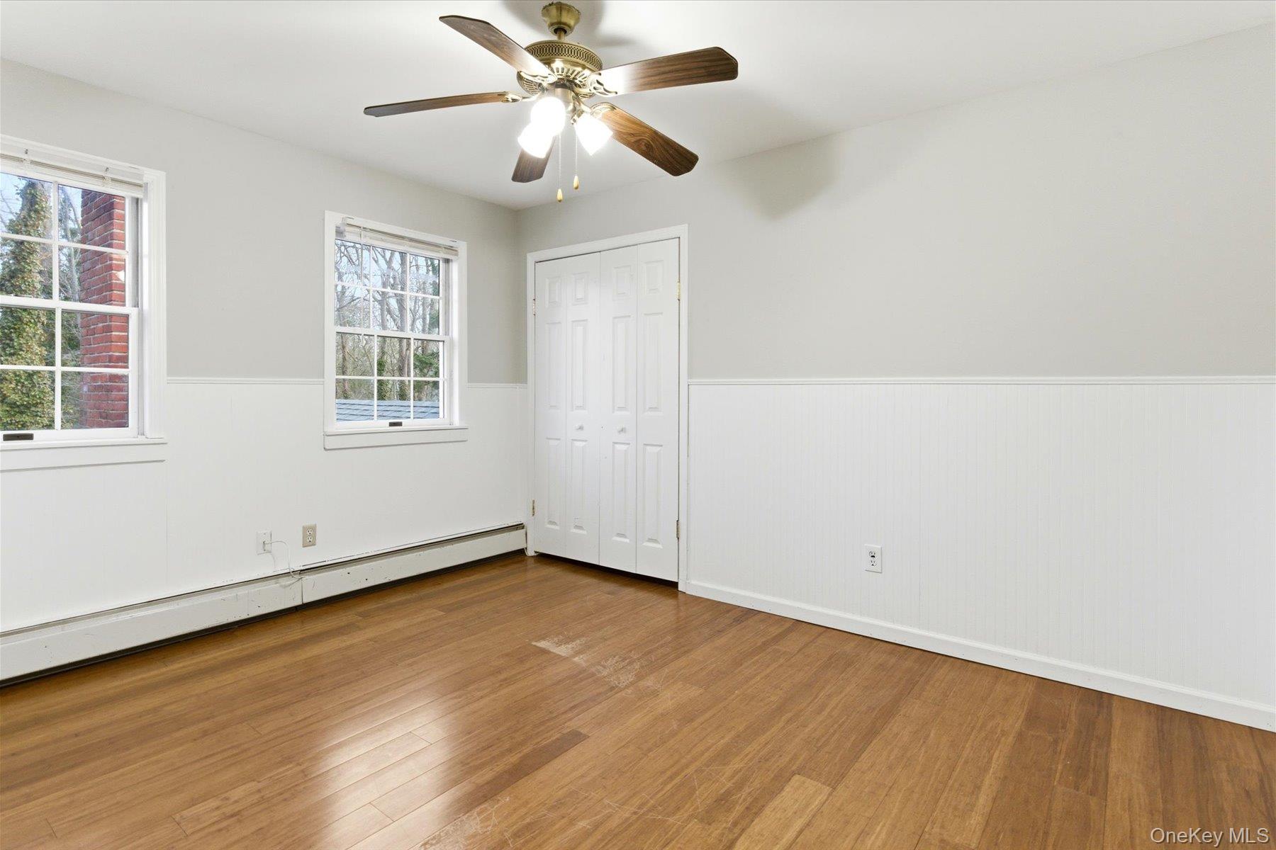 45 Eastwood Road Miller Place, NY 11764 - Photo 23 of 45 an empty room with wooden floor chandelier fan and windows