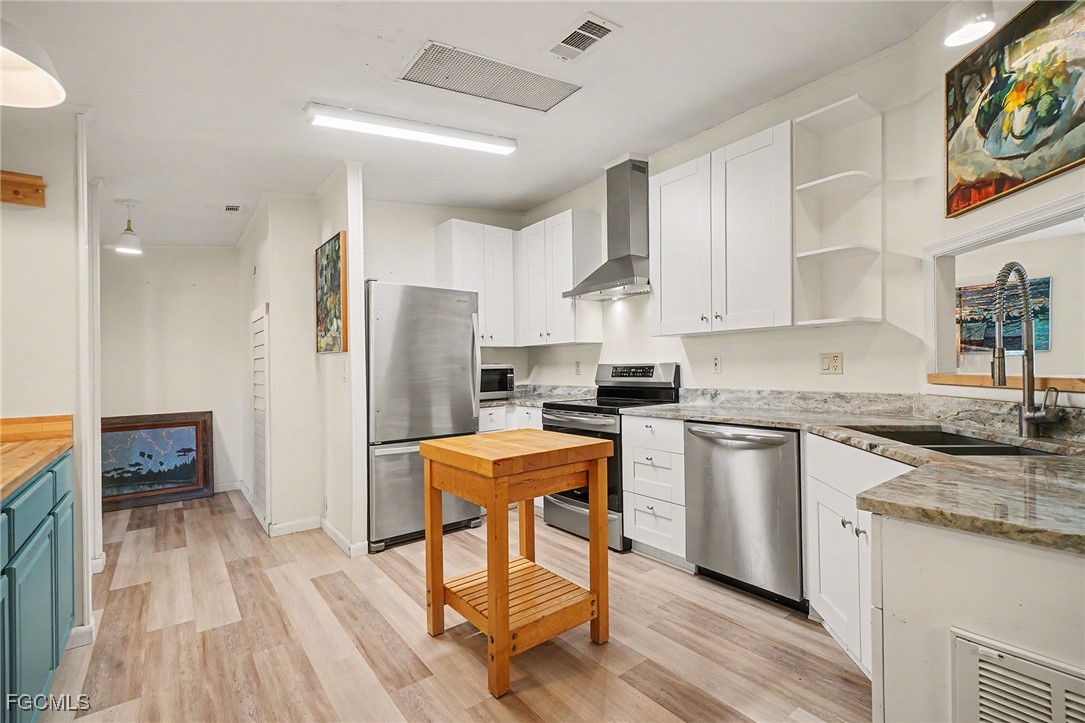 5228 Stringfellow Road St. James City, FL 33956 - Photo 7 of 35 a kitchen with stainless steel appliances granite countertop a refrigerator a stove top oven a sink dishwasher and white cabinets with wooden floor