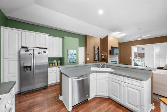 a kitchen with stainless steel appliances granite countertop a refrigerator a sink dishwasher and white cabinets with wooden floor