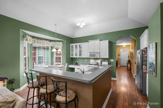 a kitchen with a table chairs stove and wooden floor