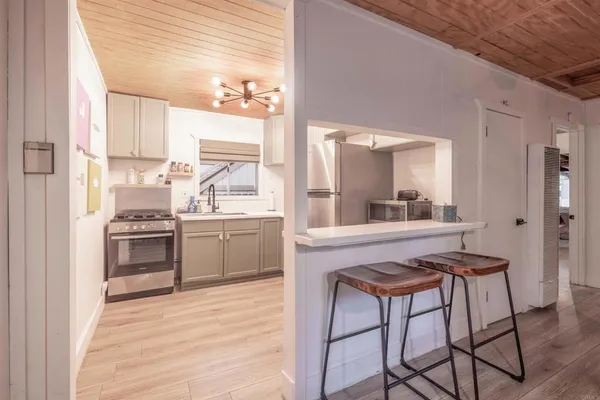 a kitchen with stainless steel appliances a stove a sink dishwasher and a refrigerator with wooden floor