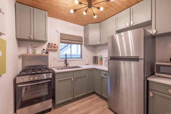 a kitchen with stainless steel appliances granite countertop a refrigerator a sink dishwasher a stove and white countertops with wooden floor