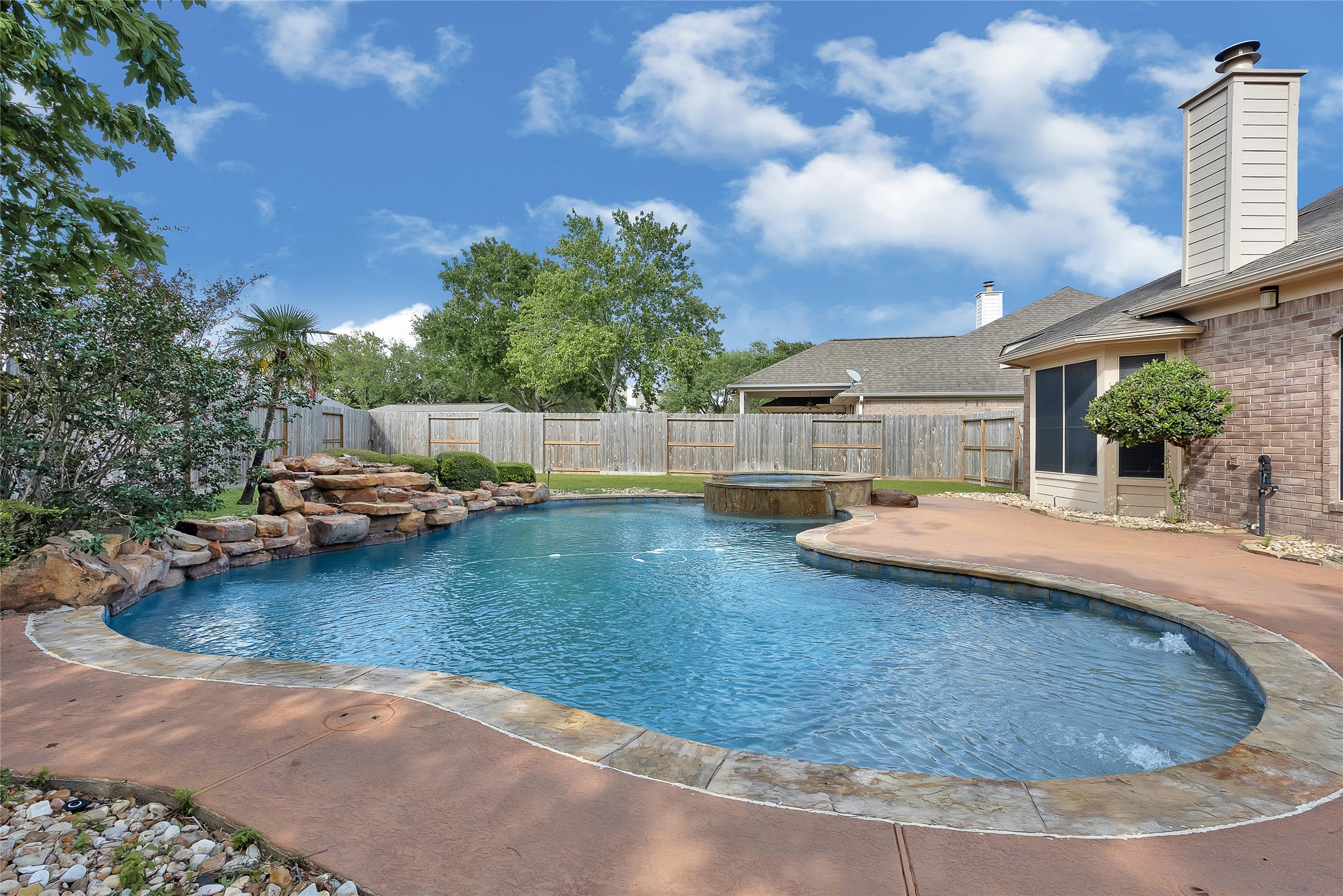 9606 Summer Run Houston, TX 77064 - Photo 39 of 41 Beautifully designed pool and spa combination with a dramatic rock ledge water feature as the focal point. Lush plants frame the perimeter, creating a private, tropical inspired retreat perfect for relaxing or entertaining.