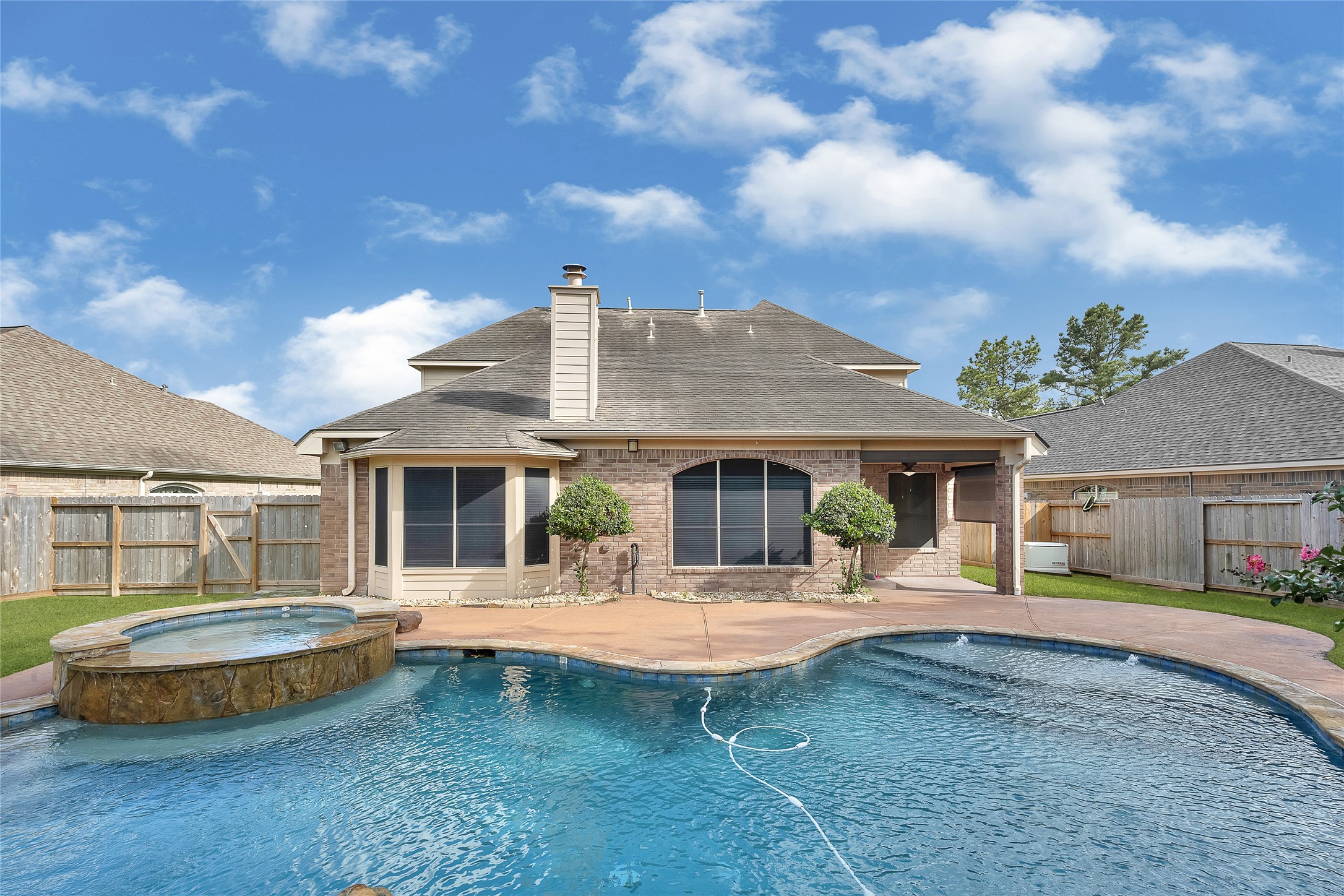 9606 Summer Run Houston, TX 77064 - Photo 39 of 41 Outdoor oasis complete with pool, elevated hot tub, and integrated rock waterfall feature. The extended backyard offers rare additional green space, while built-in outdoor speakers enhance the atmosphere for gatherings and everyday enjoyment.