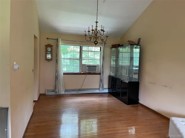 a view of a room with wooden floor front door and windows