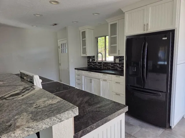 a kitchen with granite countertop a refrigerator and a sink