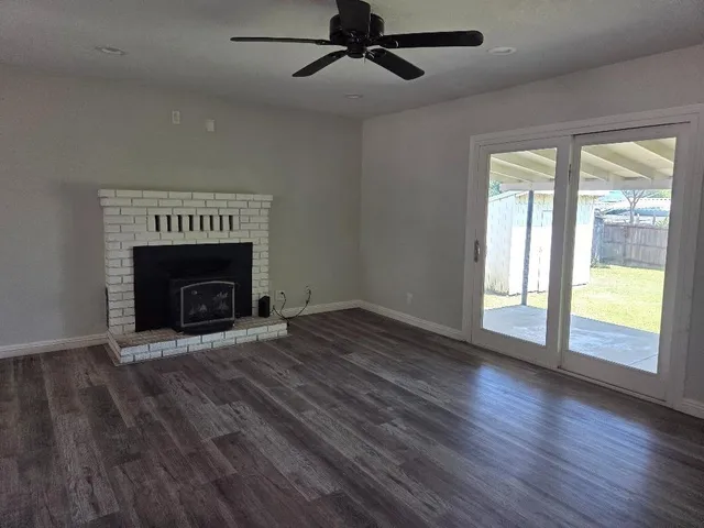 an empty room with wooden floor fireplace and windows