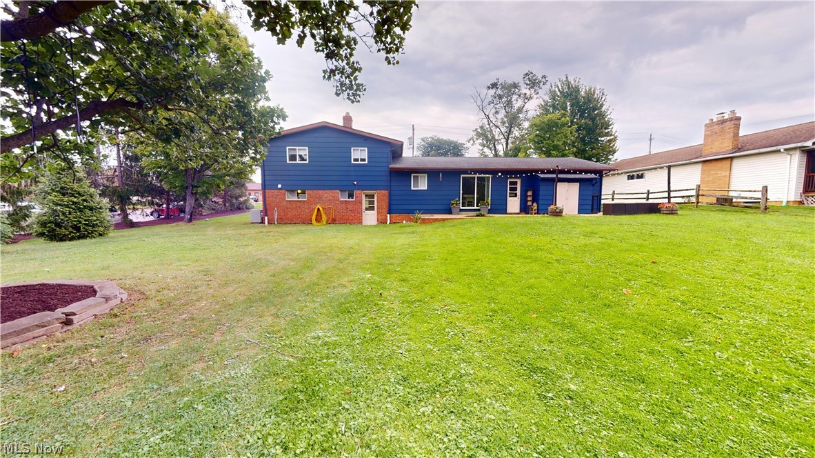 9260 Avery Road Broadview Heights, OH 44147 - Photo 36 of 43 Expansive grassy yard with mature trees, a raised garden bed, and a two-story residence with blue siding and brick accents