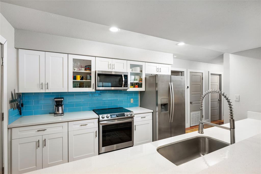 2210 Red Fox Road Austin, TX 78734 - Photo 14 of 40 A vibrant blue tile backsplash brightens this modern kitchen, featuring stainless steel appliances and abundant cabinetry.