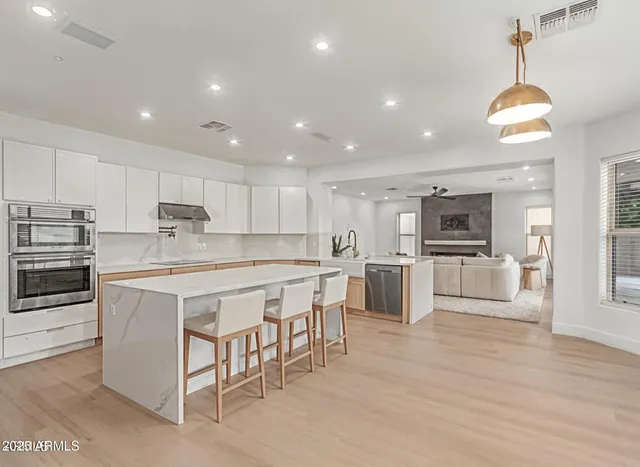 a large kitchen with kitchen island white cabinets and stainless steel appliances
