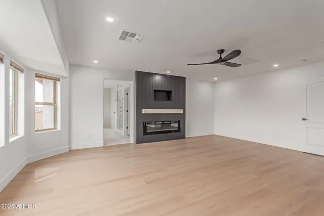 a view of an empty room with a window and kitchen view