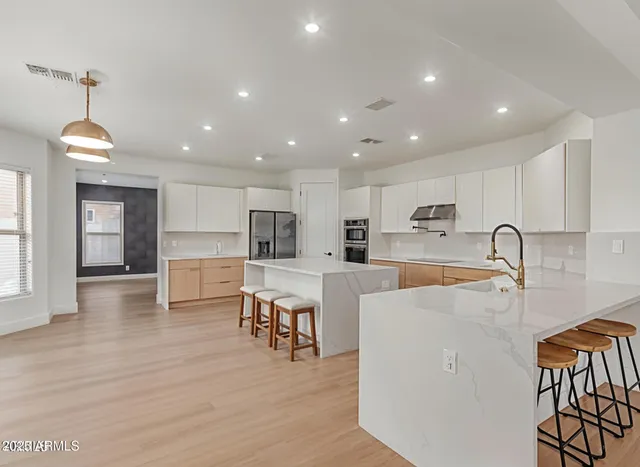 a kitchen with stainless steel appliances granite countertop a refrigerator oven a sink dishwasher and white cabinets with wooden floor