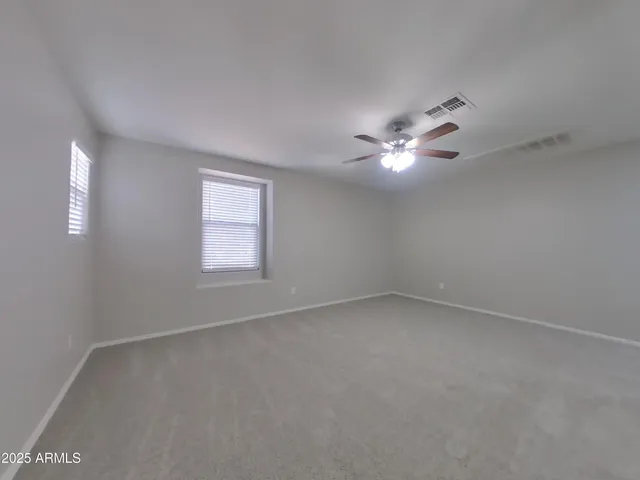 an empty room with a window and a ceiling fan