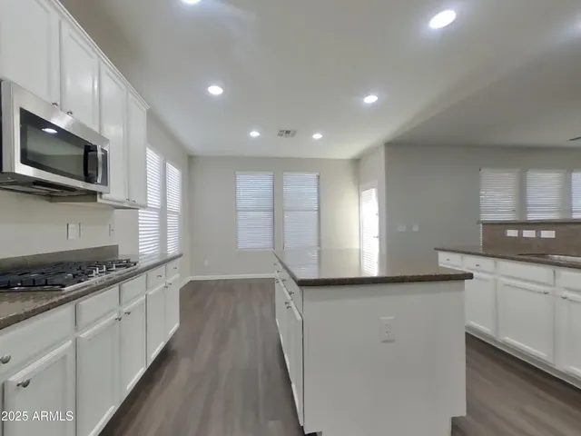 a kitchen with granite countertop a sink a stove top oven and wooden floor