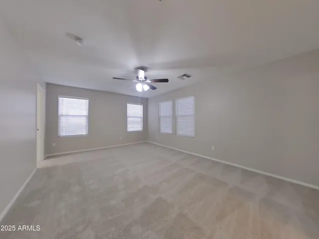 en empty room with windows and chandelier fan