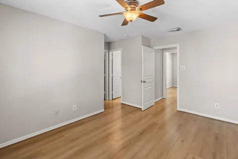 an empty room with wooden floor closet and windows
