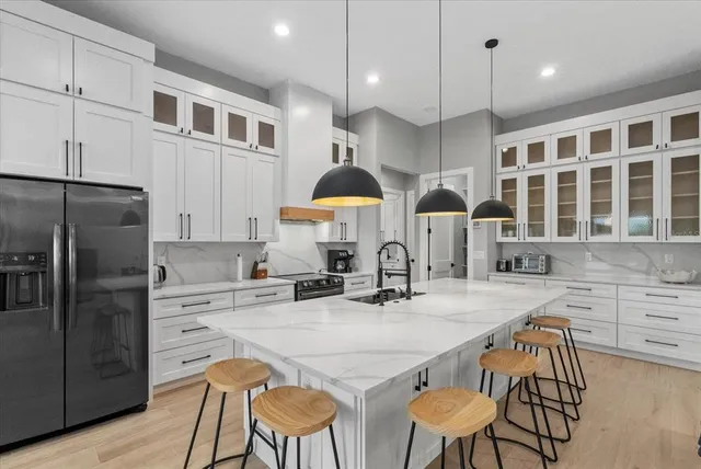 a kitchen with stainless steel appliances granite countertop a sink a stove and a wooden floors