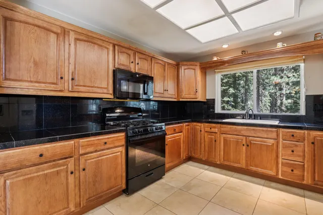 a kitchen with granite countertop a sink stainless steel appliances and cabinets