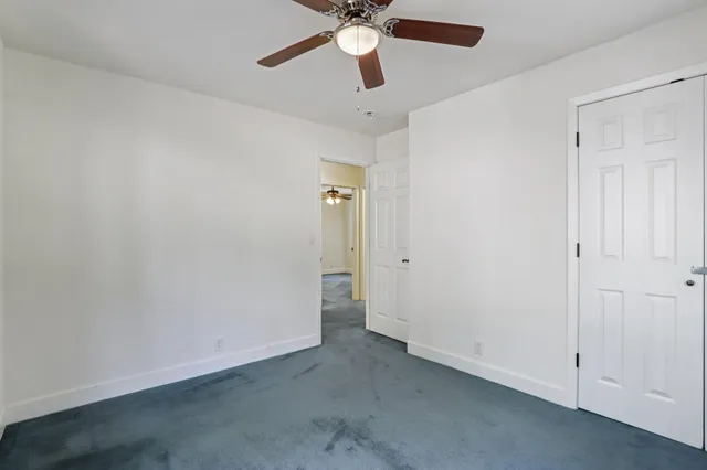 an empty room with a window and a ceiling fan