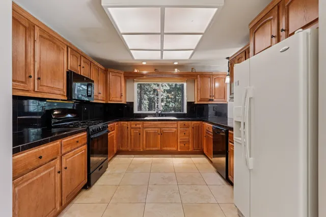 a large kitchen with stainless steel appliances granite countertop a stove a sink dishwasher and a refrigerator