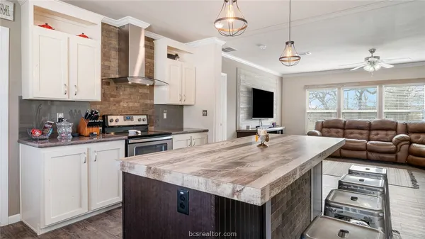 a kitchen with stainless steel appliances kitchen island granite countertop a sink a refrigerator and cabinets