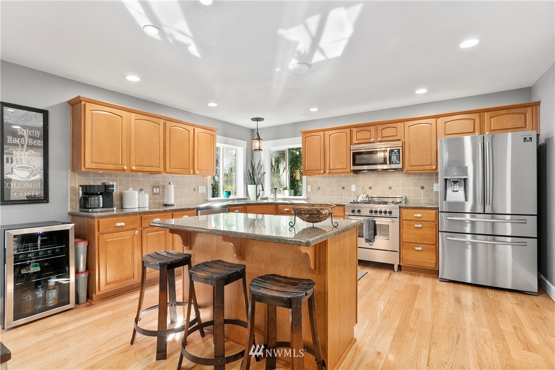 27515 Rose Road Arlington, WA 98223 - Photo 8 of 34 a kitchen with stainless steel appliances granite countertop a refrigerator a stove top oven a sink dishwasher and white cabinets with wooden floor