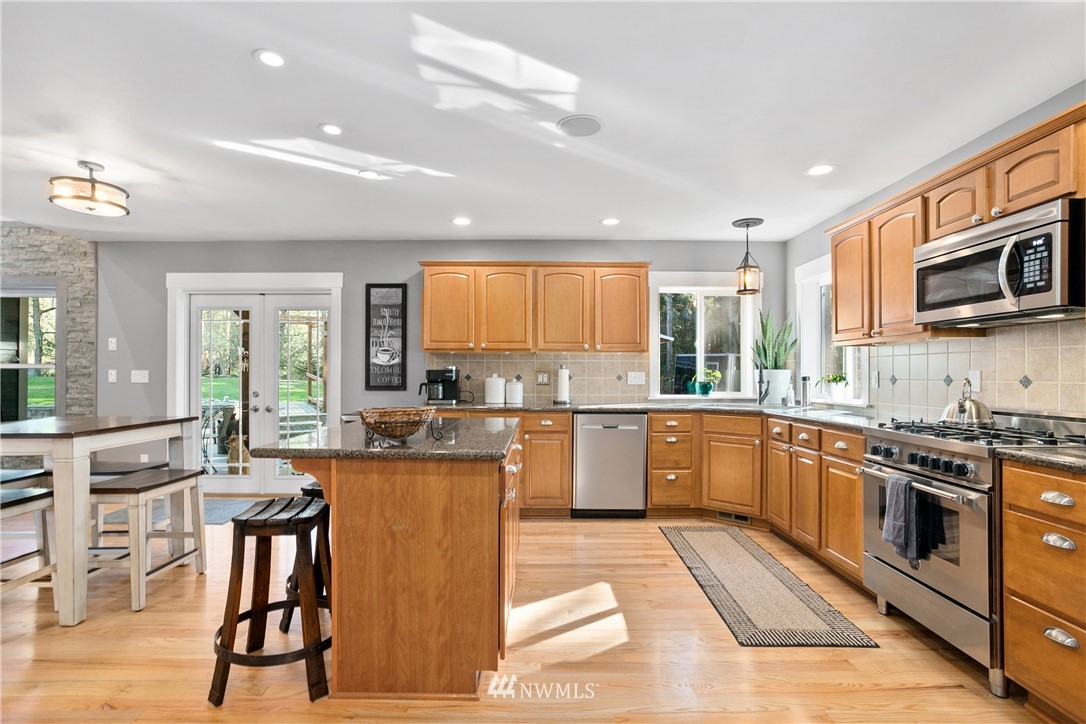27515 Rose Road Arlington, WA 98223 - Photo 9 of 34 a kitchen with stainless steel appliances granite countertop wooden cabinets a sink a stove a dining table and chairs