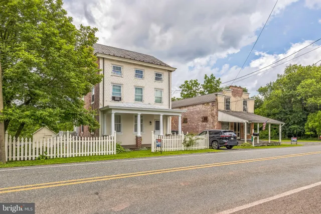 a front view of a building with a garden and trees