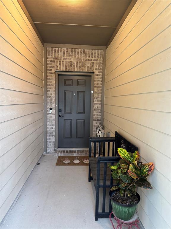 2209 Cinnamon Spgs Road Glenn Heights, TX 75154 - Photo 5 of 28 Entryway featuring a dark paneled door framed by brick detailing, light-colored horizontal siding, and a concrete porch