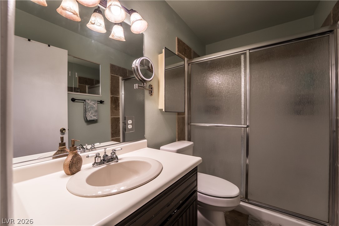 1324 Appaloosa Road Boulder City, NV 89005 - Photo 21 of 42 Well-appointed bathroom features a single vanity, a shower with frosted glass doors, and practical fixtures.