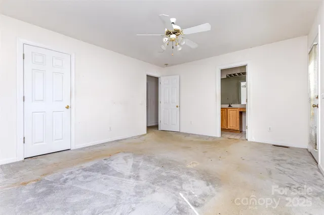 a view of an empty room with a chandelier fan