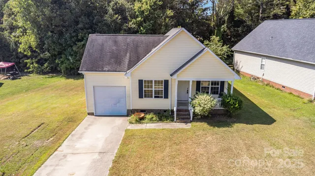 a front view of house with yard and trees in the background