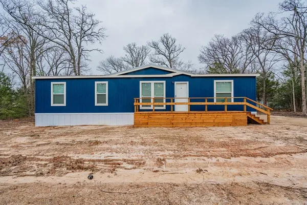 a front view of house with yard and trees around