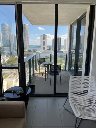 a living room with couches and balcony view with a floor to ceiling window next to a yard