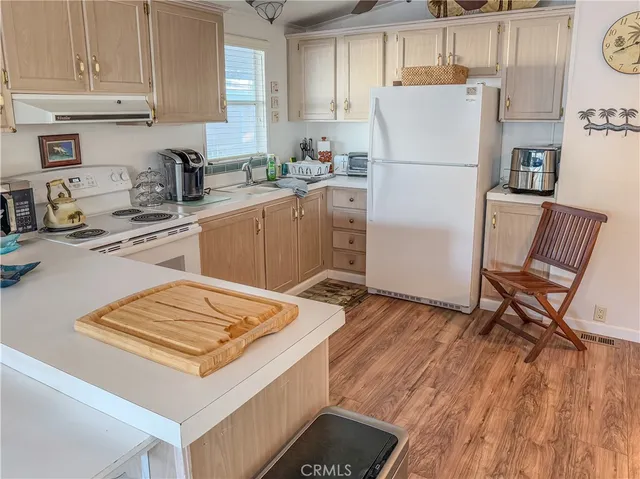 a kitchen with a refrigerator a stove a sink dishwasher and white cabinets with wooden floor