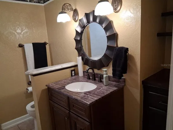 a bathroom with a granite countertop sink a toilet a mirror and shower