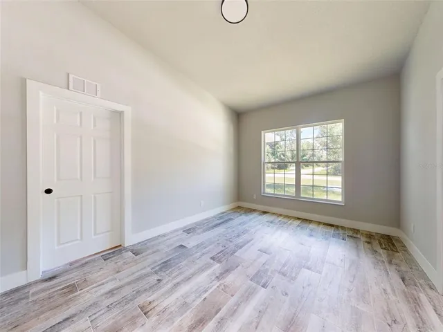 a view of an empty room with a window and wooden floor