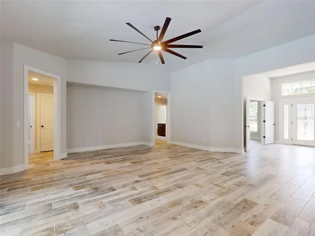 a view of empty room with wooden floor and ceiling fan