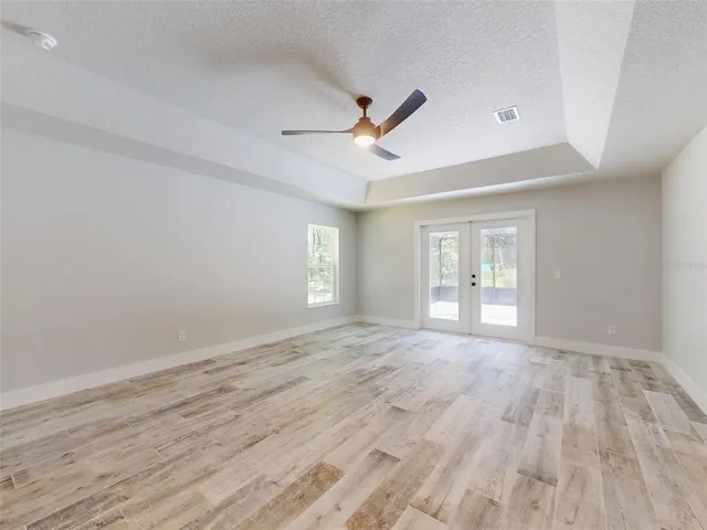 an empty room with wooden floor ceiling fan and windows