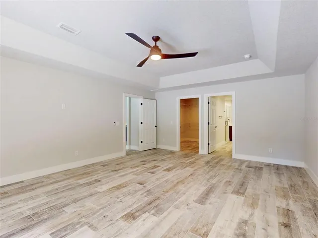 an empty room with ceiling fan and wooden floor