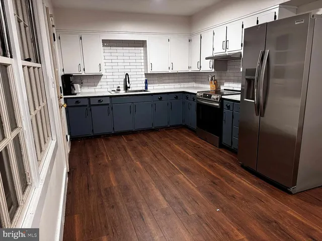 a kitchen with stainless steel appliances granite countertop a refrigerator a sink dishwasher a stove and white countertops with wooden floor