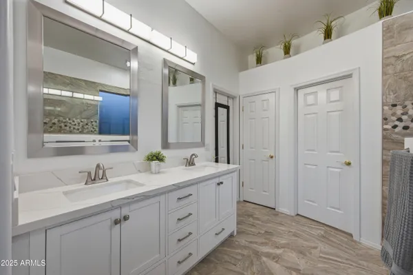 a spacious bathroom with a double vanity sink a mirror and a shower