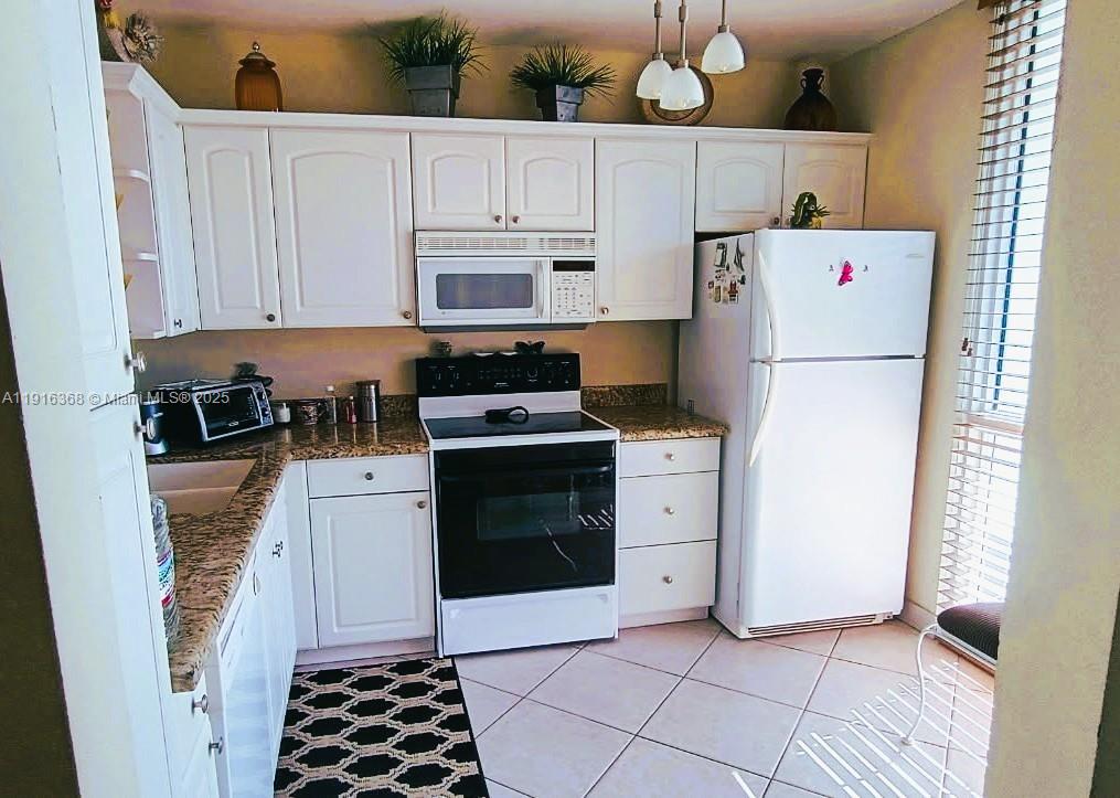 521 North Riverside Drive, Unit 907 Pompano Beach, FL 33062 - Photo 10 of 23 a kitchen with a refrigerator a stove top oven and cabinets