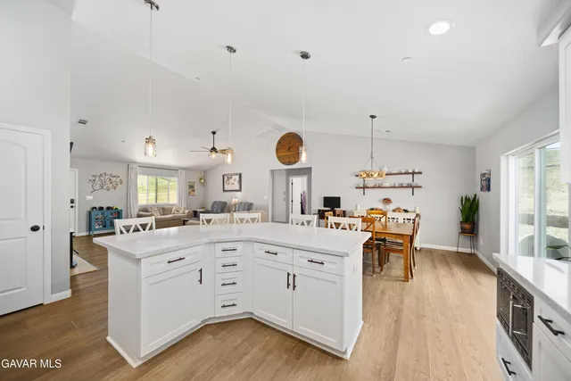 a open kitchen with stainless steel appliances granite countertop a refrigerator a stove top oven a sink dishwasher and white cabinets with wooden floor