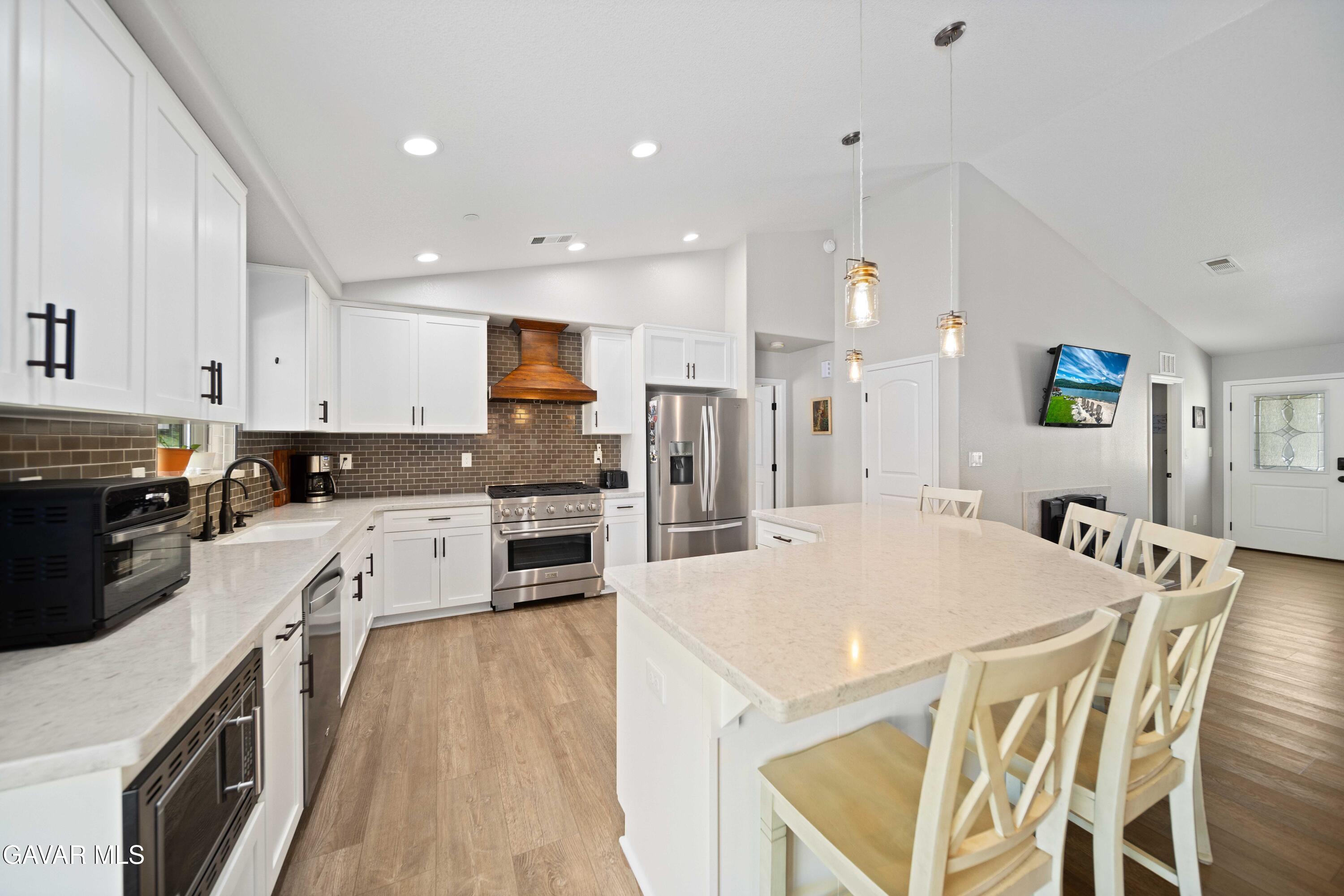 29990 Horsethief Drive Tehachapi, CA 93561 - Photo 12 of 29 a open kitchen with stainless steel appliances granite countertop a refrigerator a stove top oven a sink dishwasher and white cabinets with wooden floor
