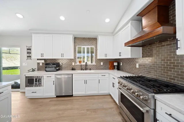 a kitchen with stainless steel appliances a white stove top oven a sink dishwasher and cabinets with wooden floor