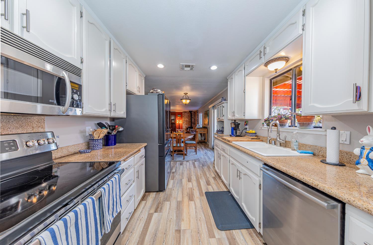 40733 Big Oak Flat Road North Oakhurst, CA 93644 - Photo 14 of 73 a kitchen with stainless steel appliances granite countertop a refrigerator a sink dishwasher a stove and white cabinets with wooden floor